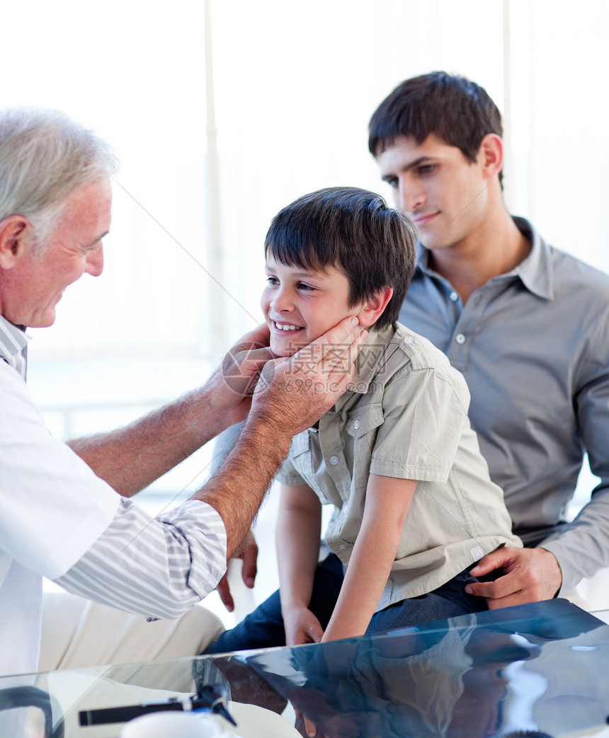 高级医生与父亲一起检查小男孩喉咙图片