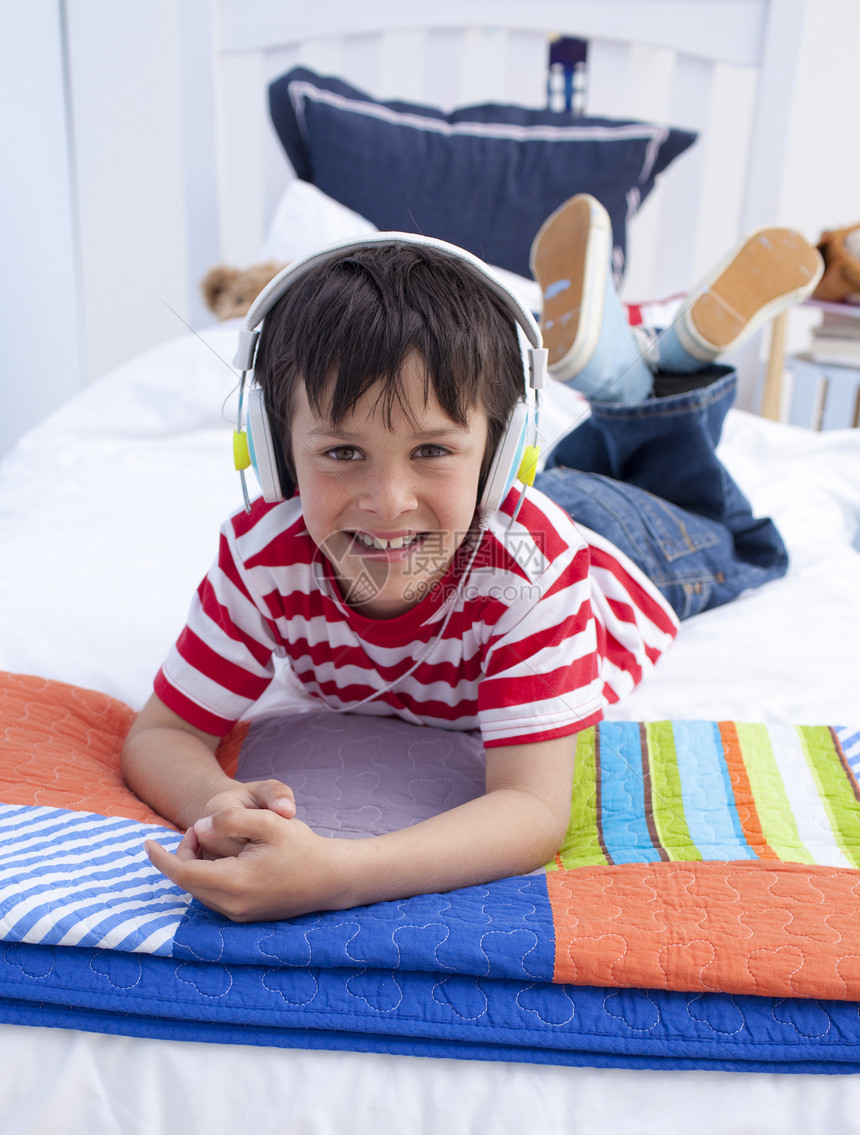 耳机上男孩的肖像 在床上听音乐图片