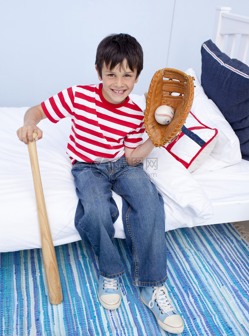 小男孩在床上打棒球了图片
