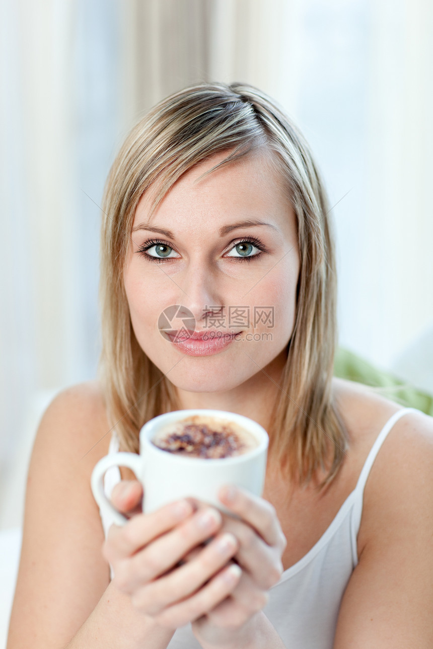 一位年轻女子坐在沙发上喝咖啡的肖像图片