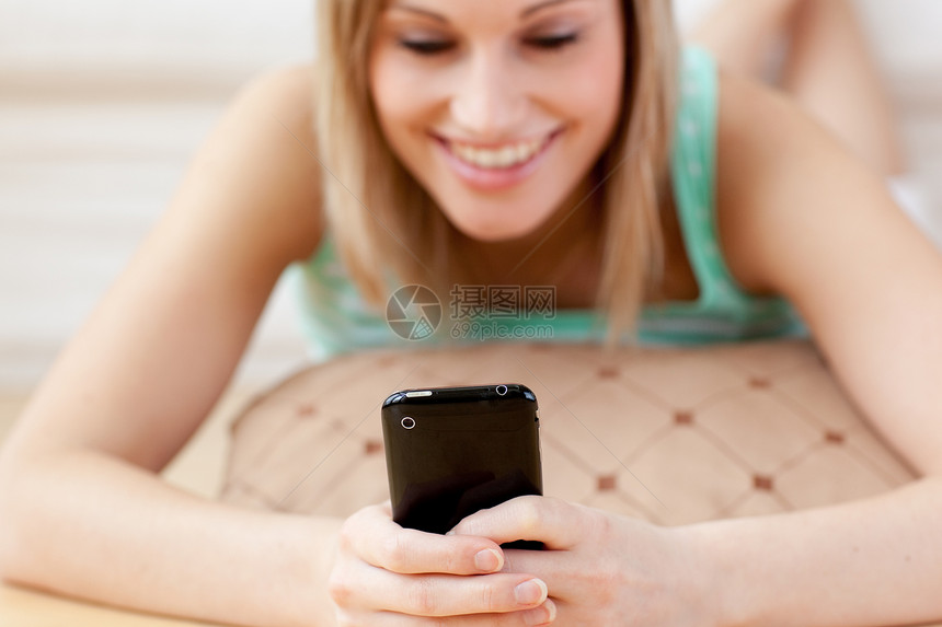 微笑的金发金发女人 在地板上发短信图片