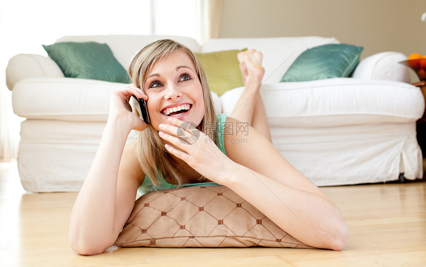 欢笑的年轻女人在电话里说话 躺在地板上图片
