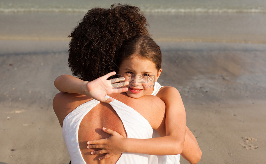 好女孩和她妈妈在沙滩上抱抱图片