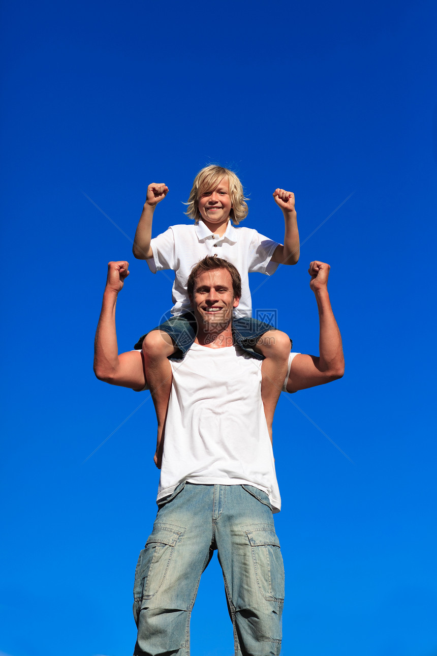 强壮的儿子坐在他父亲的肩上图片