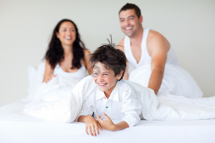家人与他儿子在床上玩耍拥抱卧室妈妈幸福乐趣说谎孩子微笑感情男人图片