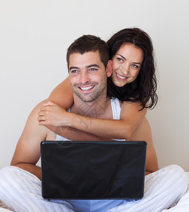 使用笔记本电脑在床上微笑的情侣男性恋人丈夫情感内饰男朋友卧室投标女朋友女性背景图片