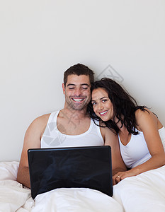 在床上使用笔记本电脑的情侣背景图片