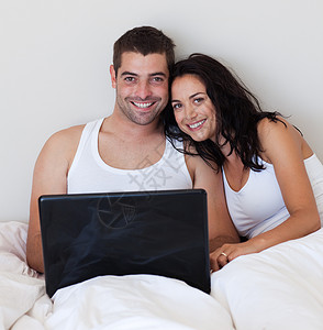 在卧室使用笔记本电脑的拉迪雅特夫妇背景图片