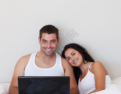 在床上使用笔记本电脑的婚配情侣背景图片