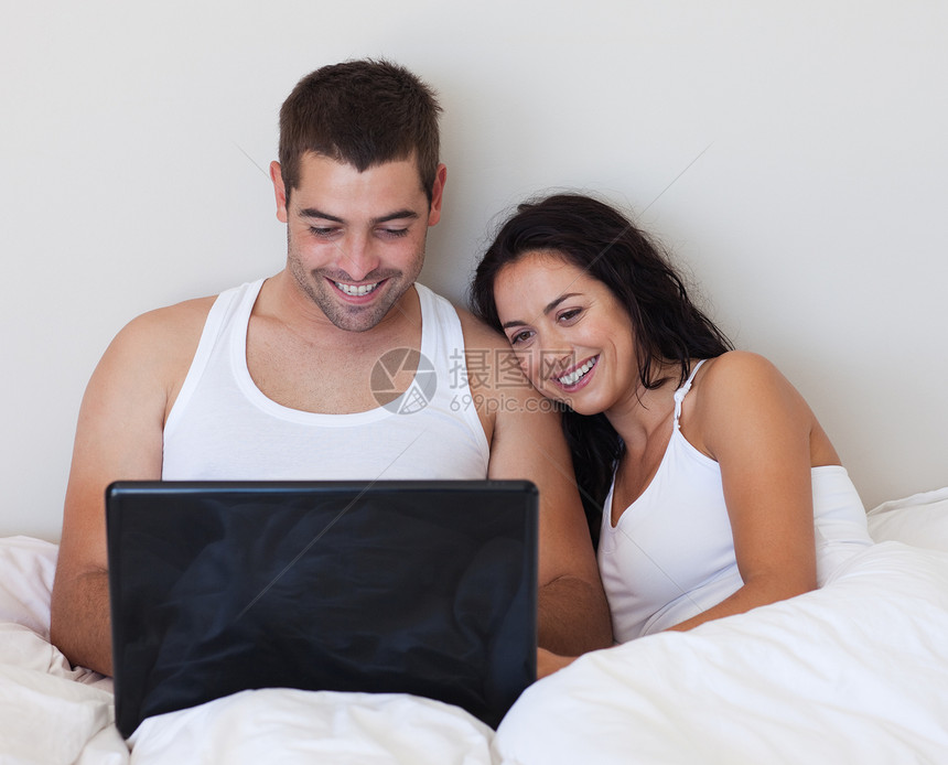 使用笔记本电脑坐在床上的情侣图片