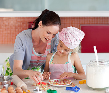 感恩的母亲和女儿在厨房烘烤家长成人教学桌子夫妻烹饪帮助糕点食物童年背景图片