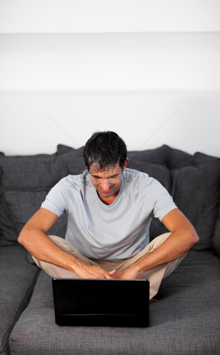 在灰色沙发上使用笔记本电脑的Radiant man图片