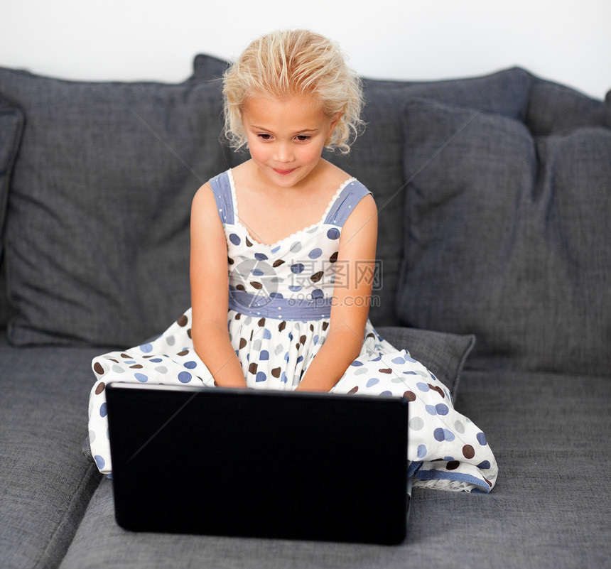 年轻女孩在沙发上用笔记本电脑图片