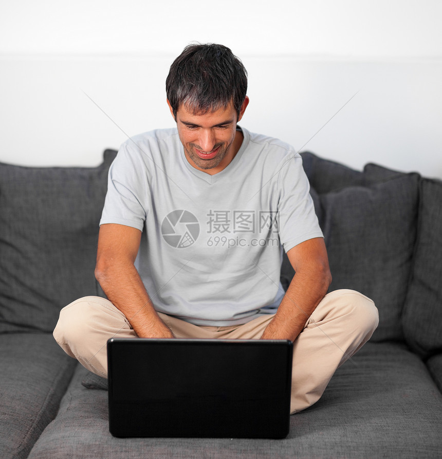 亮人用笔记本电脑在灰色沙发上图片