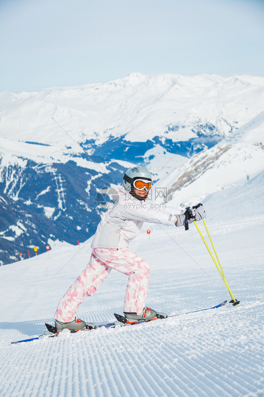 快乐的小女孩在下坡滑雪青年女性女孩配备季节天空活动套装衣服头盔图片
