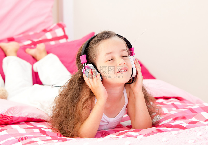美丽的小女孩听音乐躺在床上的床铺上图片