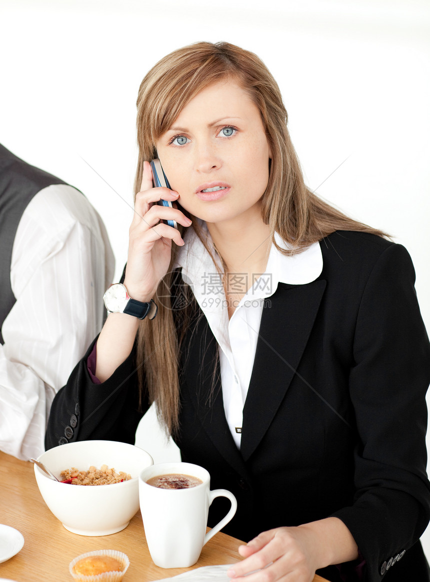 担心的女商务人士在吃早餐时通过电话交谈图片