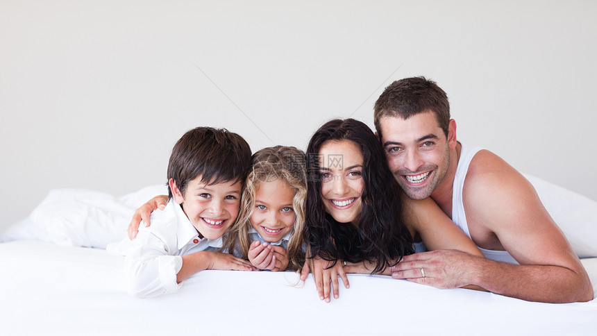 幸福的一家人躺在床上玩乐父母孩子女性女孩卧室妈妈生活男人乐趣说谎图片