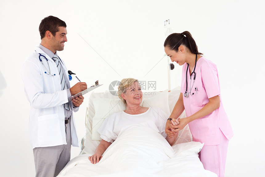 微笑的病人躺在友好的护士和医生之间图片