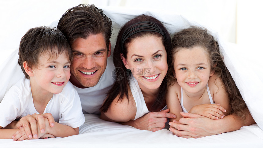 一个微笑的家庭躺在床上的肖像图片