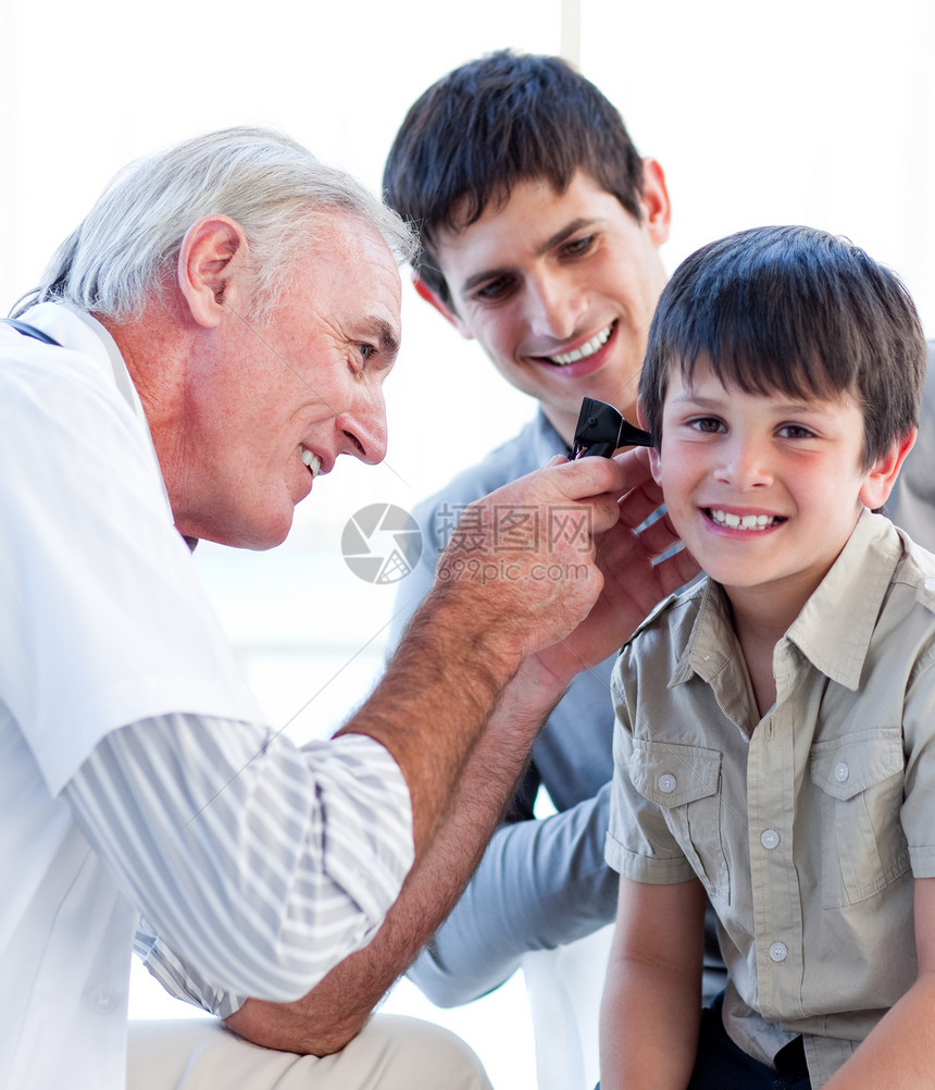 高级医生检查一个小男孩的耳朵图片