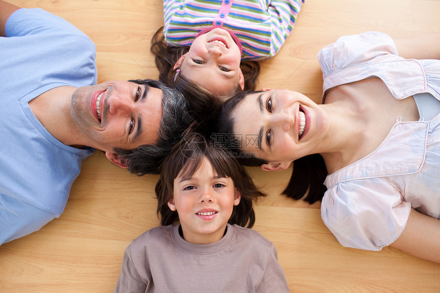 微笑的年轻家庭躺在地板上 头和头一起笑图片