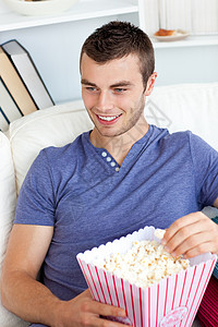 在沙发上吃爆米花的caucasians男人背景图片