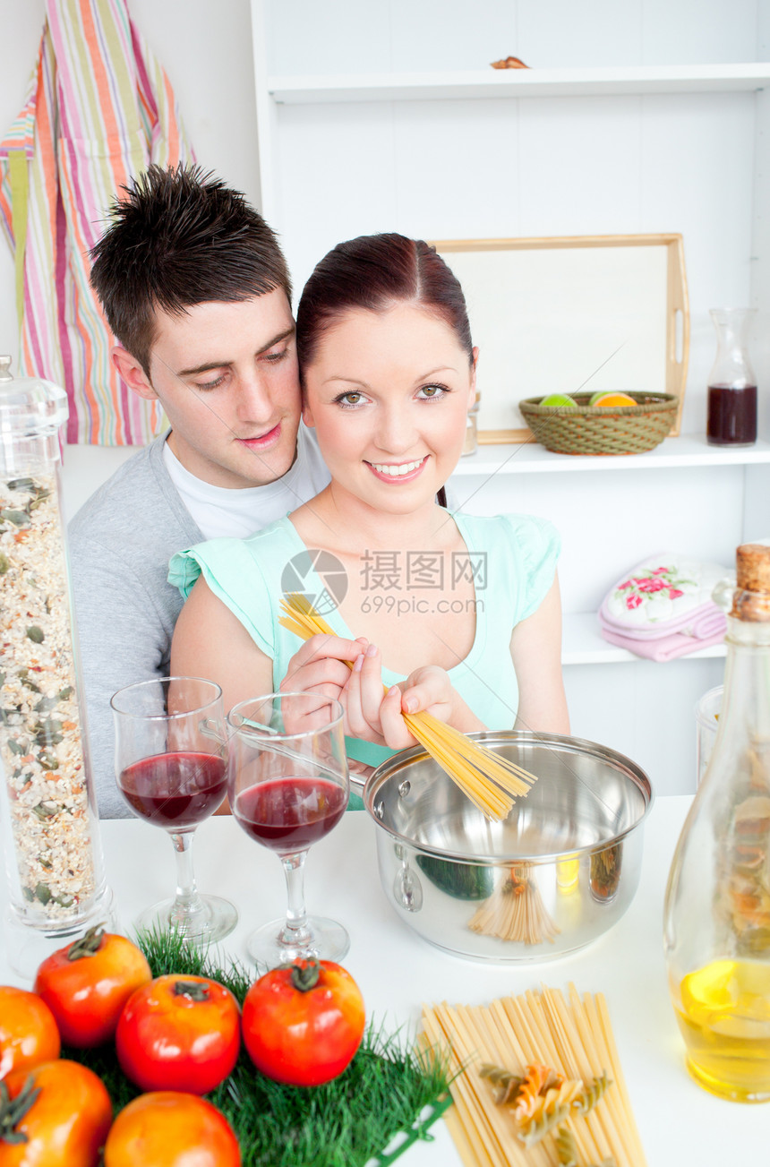 年轻夫妇在厨房里准备意大利面和喝红酒图片
