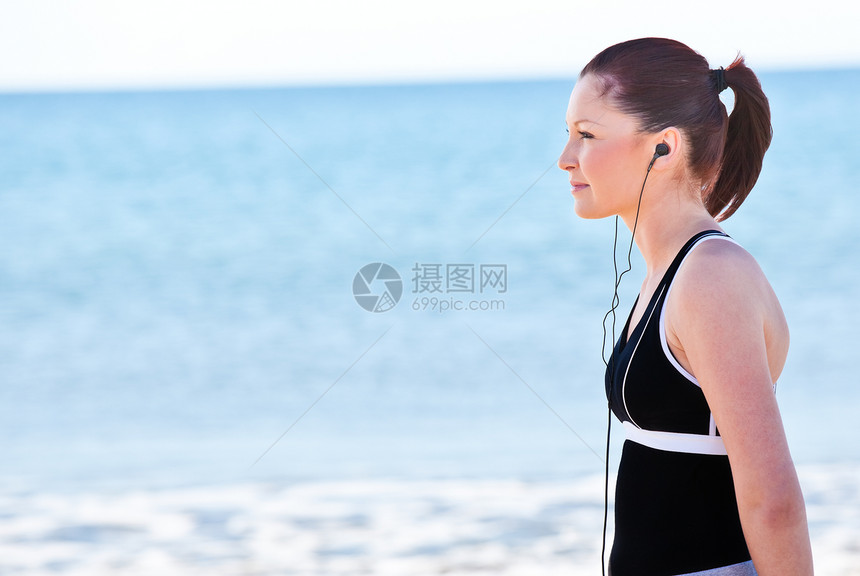 在海滩上听音乐的年轻女子图片