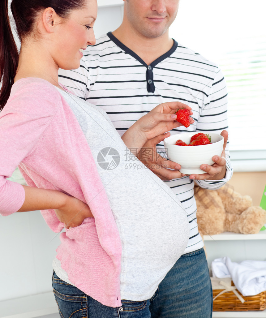 一位快乐的孕妇吃草莓和O的肖像图片