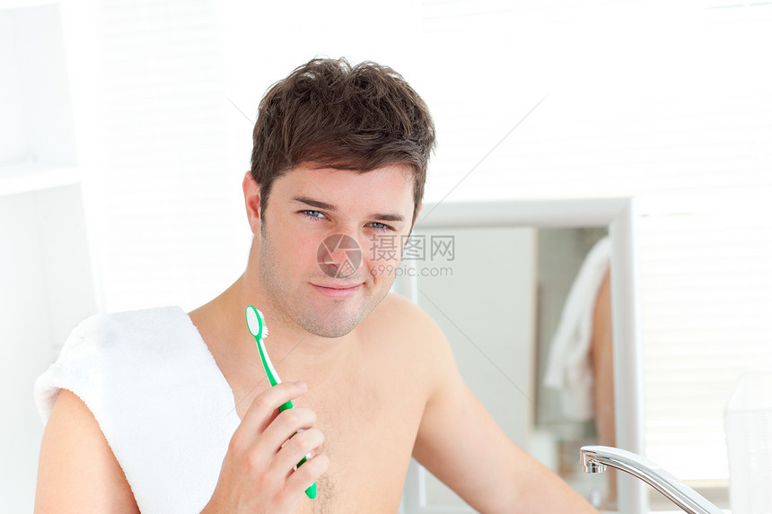 微笑的年轻人 用毛巾在浴袍里刷牙图片