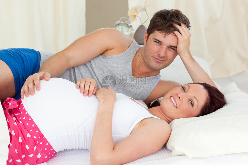 与丈夫在床上躺着的Caucasians孕妇快乐图片