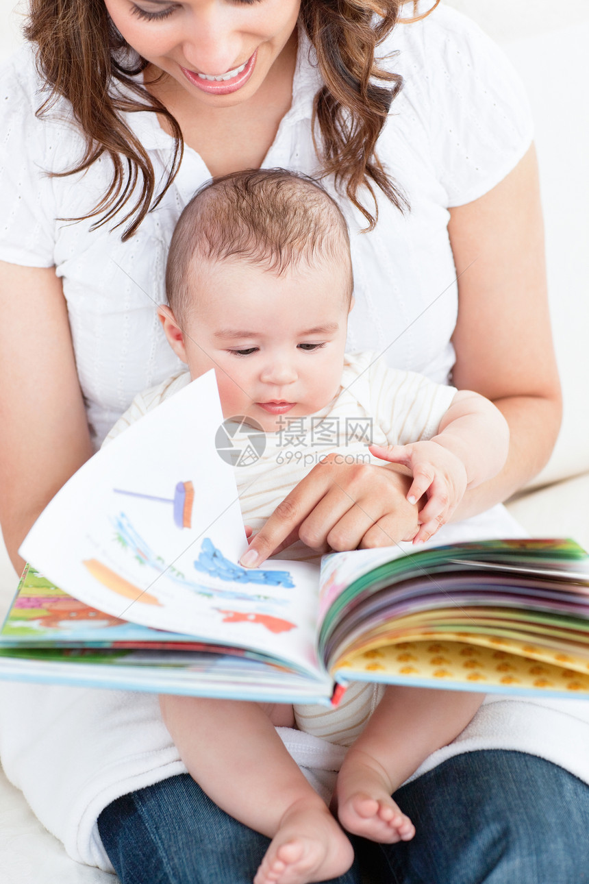 快乐的母亲给坐在沙发上的孩子看一本书图片