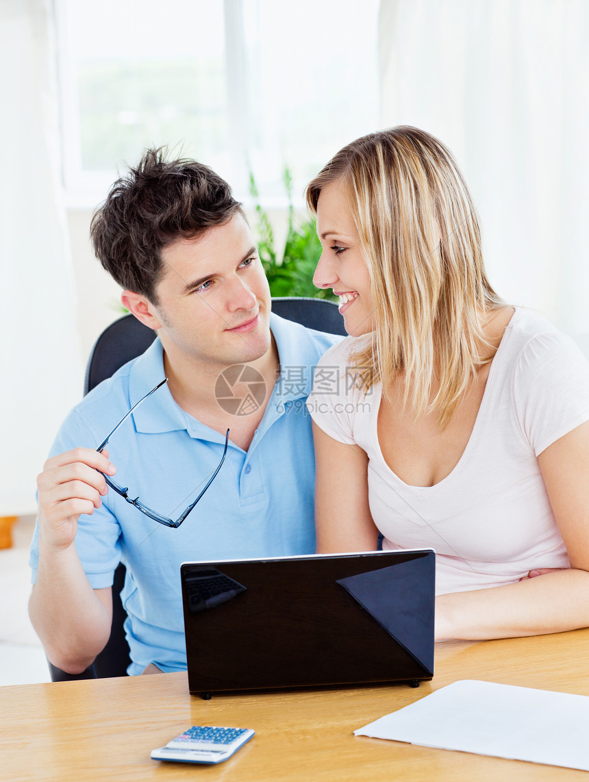可爱的一对情侣坐在一起坐在一张桌子上 在笔记本电脑wi上工作图片