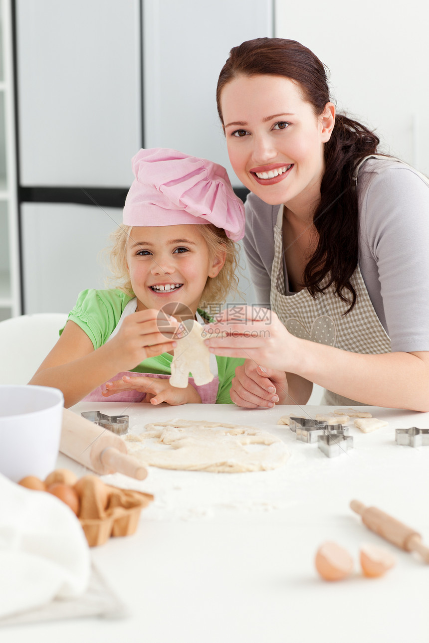 快乐的女孩和母亲一起烤小蛋糕图片