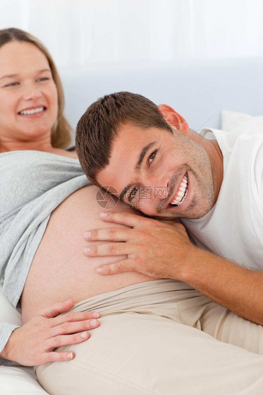 快乐的男人听着他怀孕妻子的肚子图片