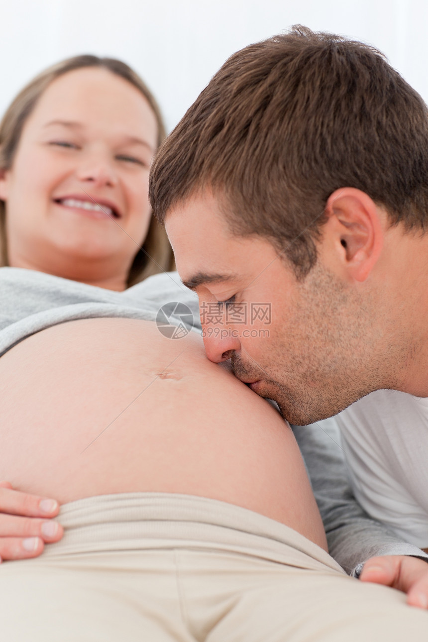 快乐的男人亲吻他怀孕妻子的肚子 同时放松图片
