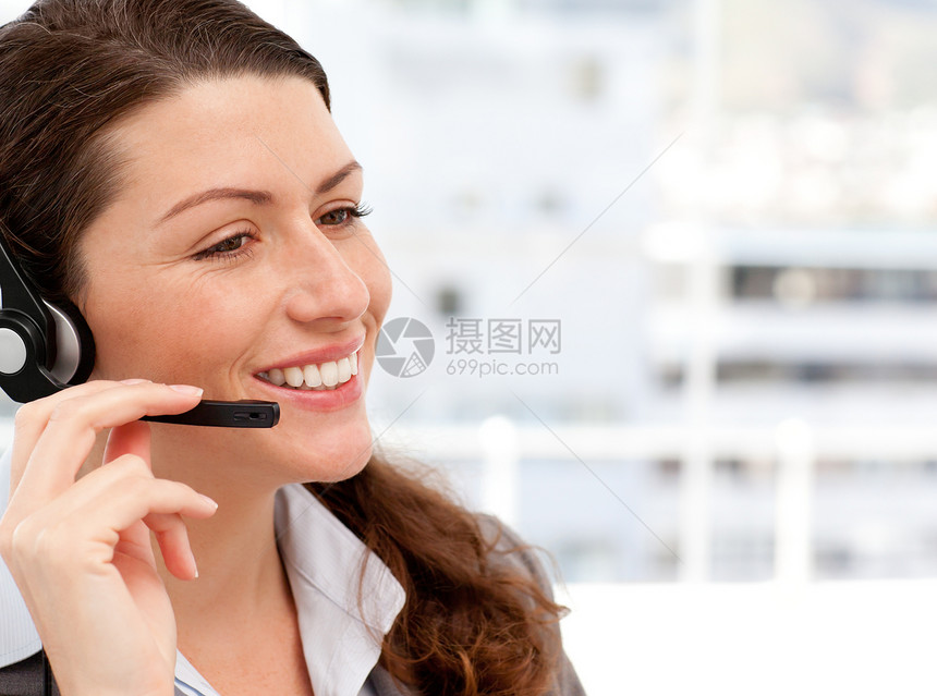 微笑的女商务人士在电话上用耳机说话图片
