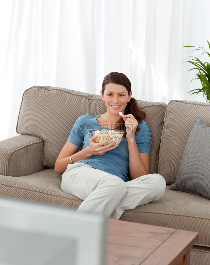 开心女人一边看电视边吃流行玉米 一边看电视图片