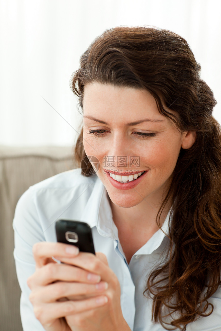 美丽的女人在沙发上发短信 坐在沙发上长椅客厅人士微笑手机技术商业商务电话黑发图片