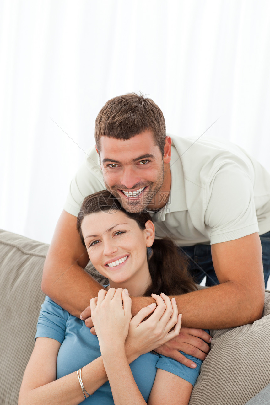 快乐的男人拥抱他的女朋友 坐在沙发上图片