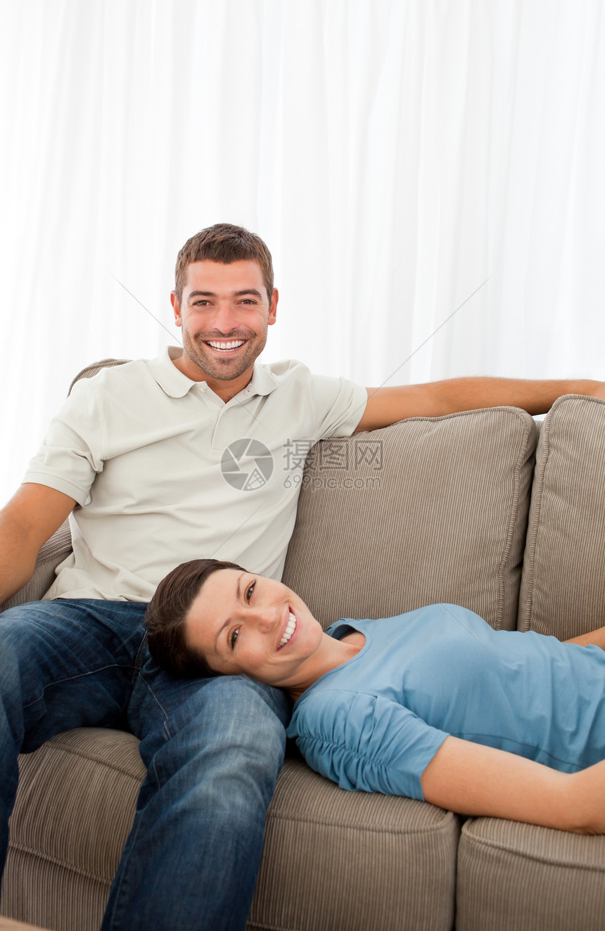 一对快乐的情侣躺在沙发上的肖像图片