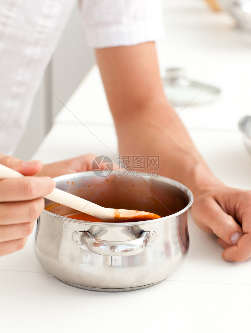 一个男人和女人在厨房里吃酱汁的近身图片