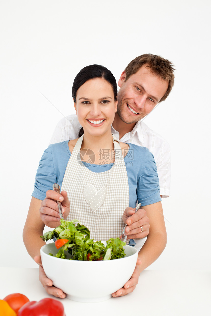 快乐的男子混合沙拉 和女友在厨房图片