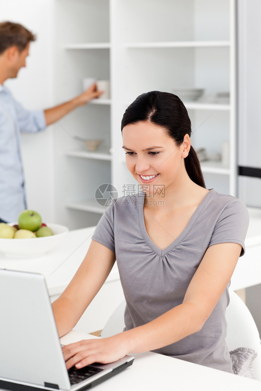 漂亮女人在笔记本电脑上工作 而她的男朋友正在寻找f图片