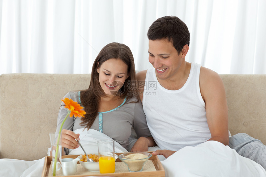 年轻女人和她男朋友在床上吃早饭的女青年图片