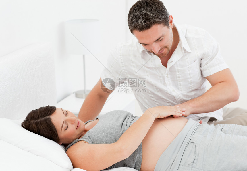与丈夫在一起的孕妇女士母亲腹部享受婴儿母性夫妻卧室几个月怀孕图片