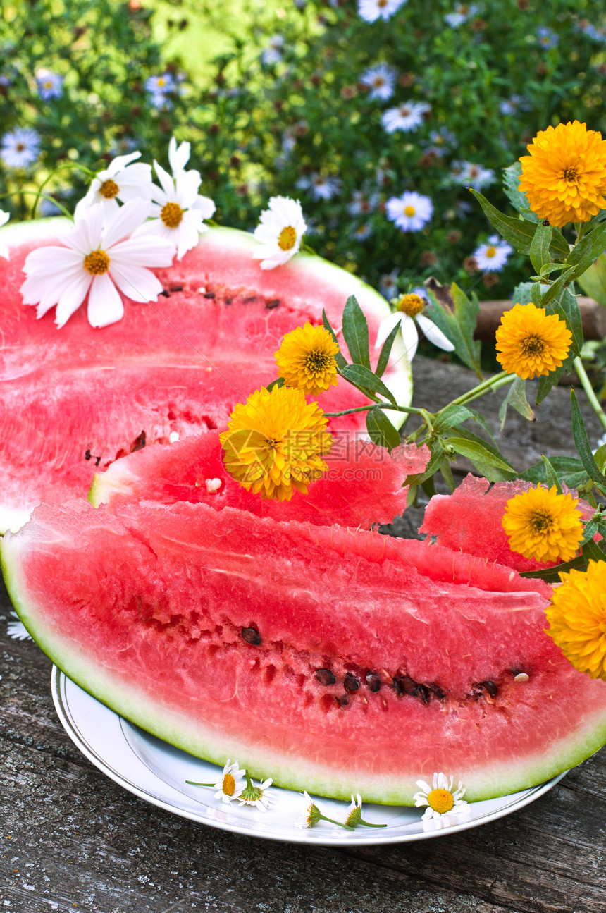 餐桌上吃着成熟的西瓜空气花朵种子粉色雏菊营养甜点饮食圆形浆果图片