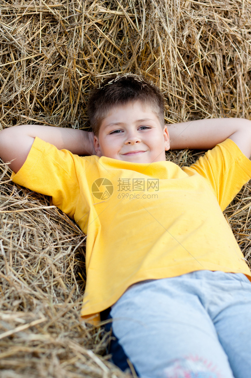 男孩躺在稻草上场地童年村庄草地休息晴天农场国家黄色生活图片