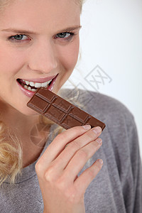 咬一口的巧克力女人吃巧克力微笑食物淑女甜点休息商品化牙齿妻子蓝绿色眼睛背景